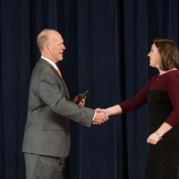 Doctor Potteiger shaking hands with an award recipient in a maroon and black dress
